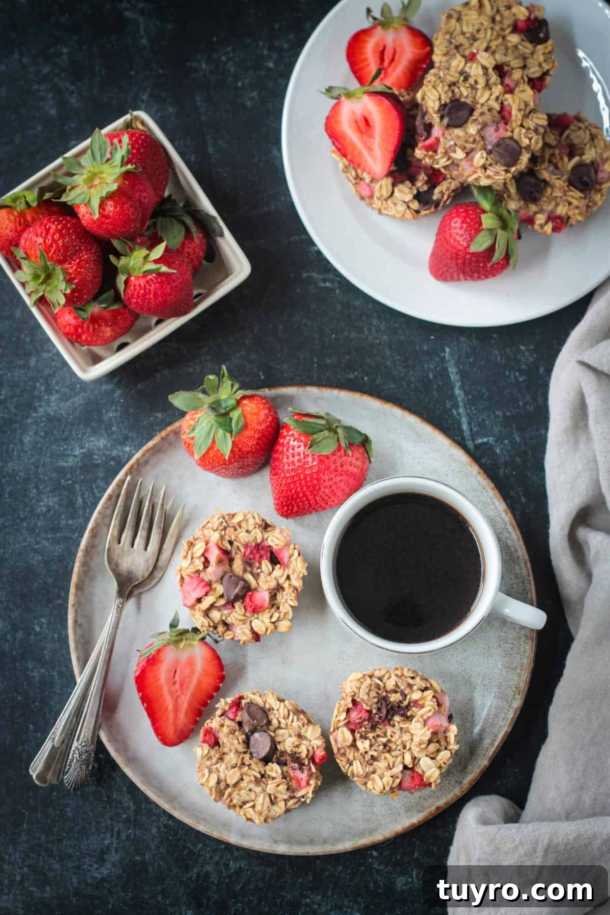 Strawberry Baked Oatmeal Muffins Three strawberry baked oatmeal muffins on a plate with a cup of coffee and fresh strawberries.