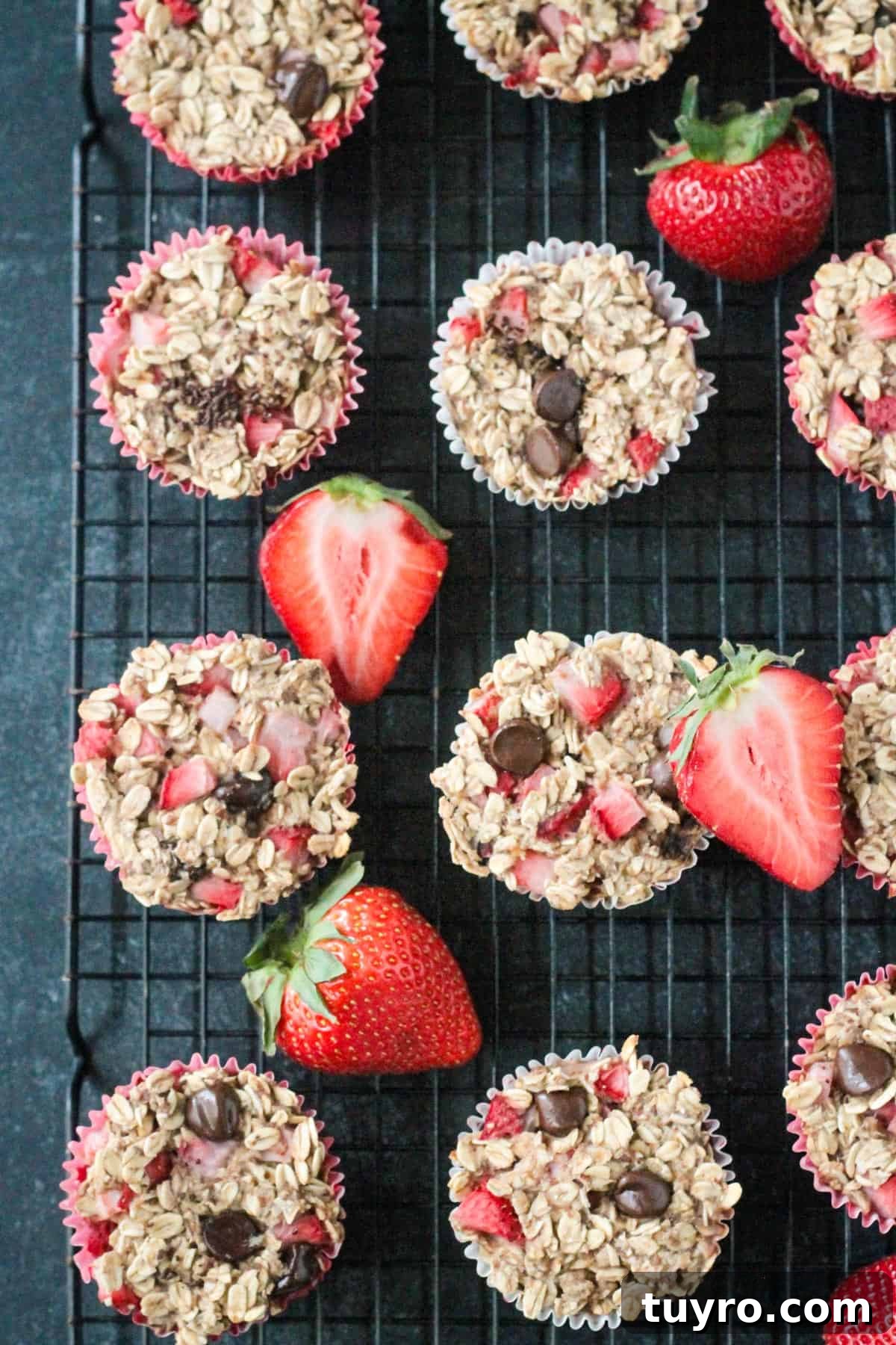Strawberry Baked Oatmeal Muffins Recipe for Moist Breakfast Bites 9 Close up of baked oatmeal muffins on a cooling rack with fresh strawberries.