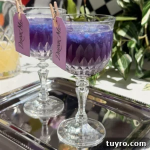 Galaxy Cotton Candy Lemonade Cocktail — Color-Changing Drink Tutorial 6 Two crystal glasses filled with purple galaxy cotton candy lemonade cocktails over blue granita.