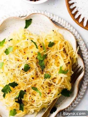 Easy air fryer spaghetti squash on a plate with fresh green herbs.