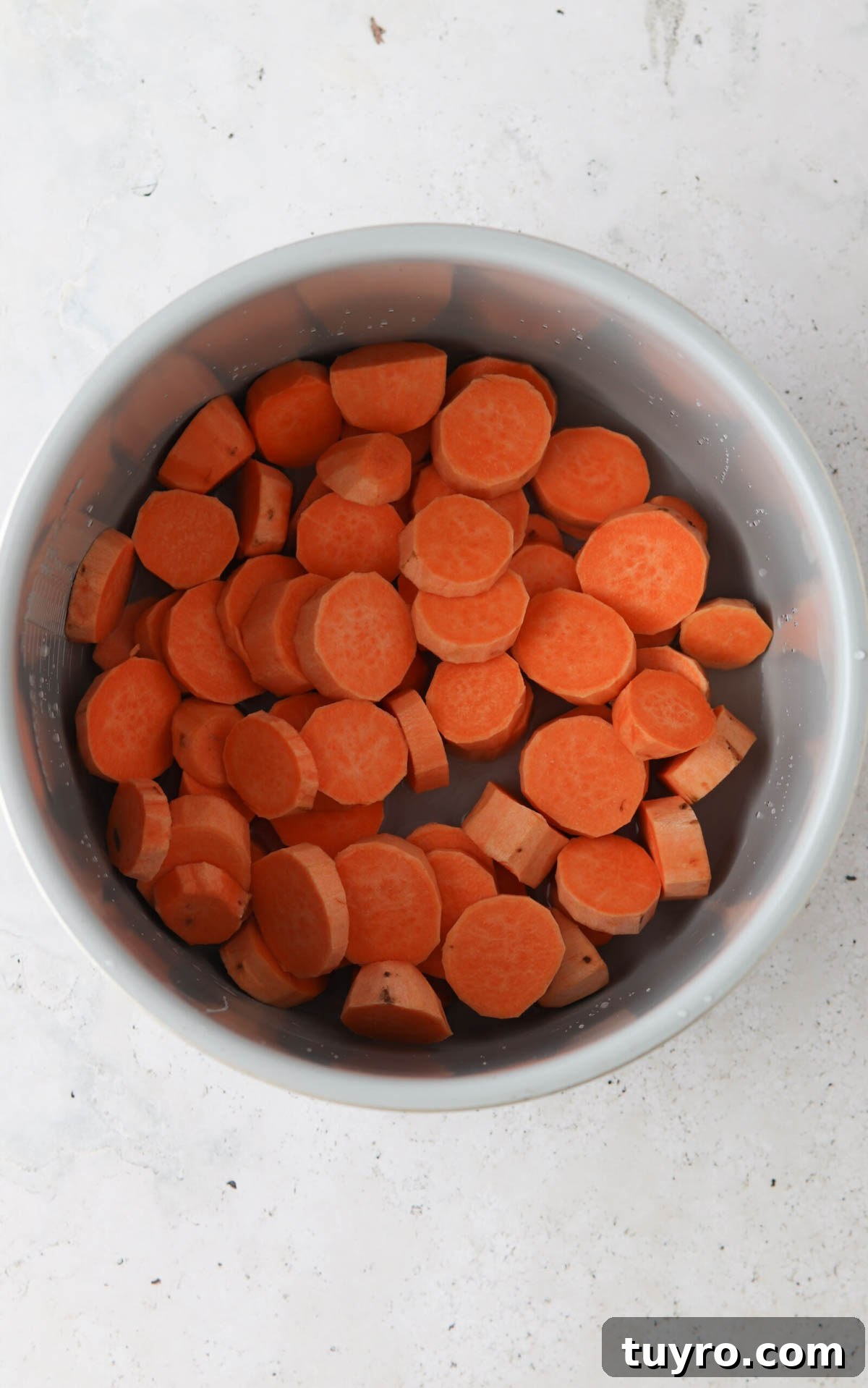 Sliced sweet potatoes in a pressure cooker base.