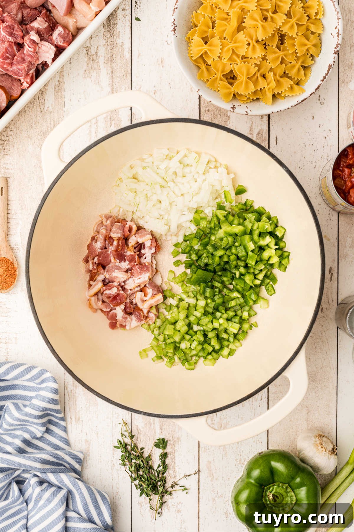 A Dutch oven with chopped onions, bell peppers and celery, with bacon.
