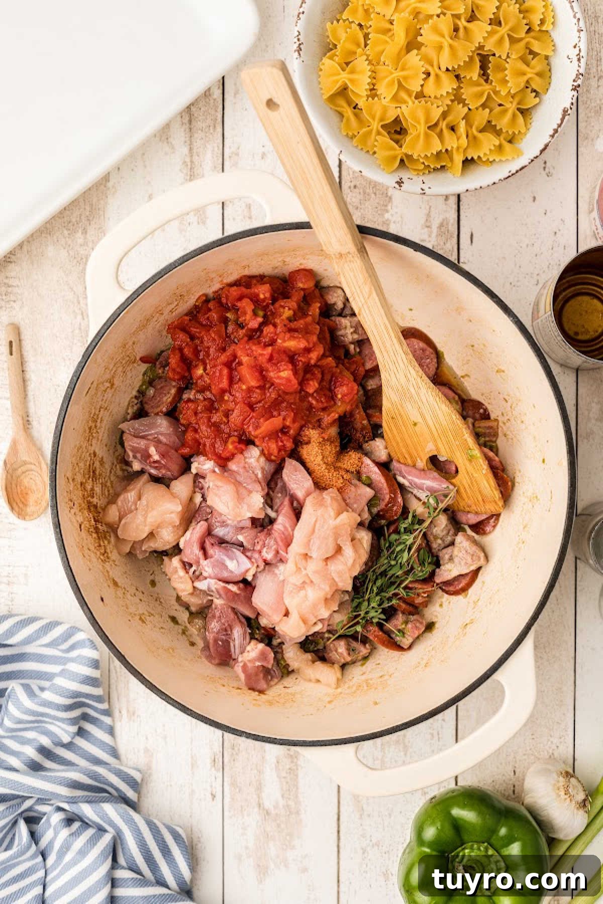 Tomatoes, chicken and seasonings being added to a Dutch oven.