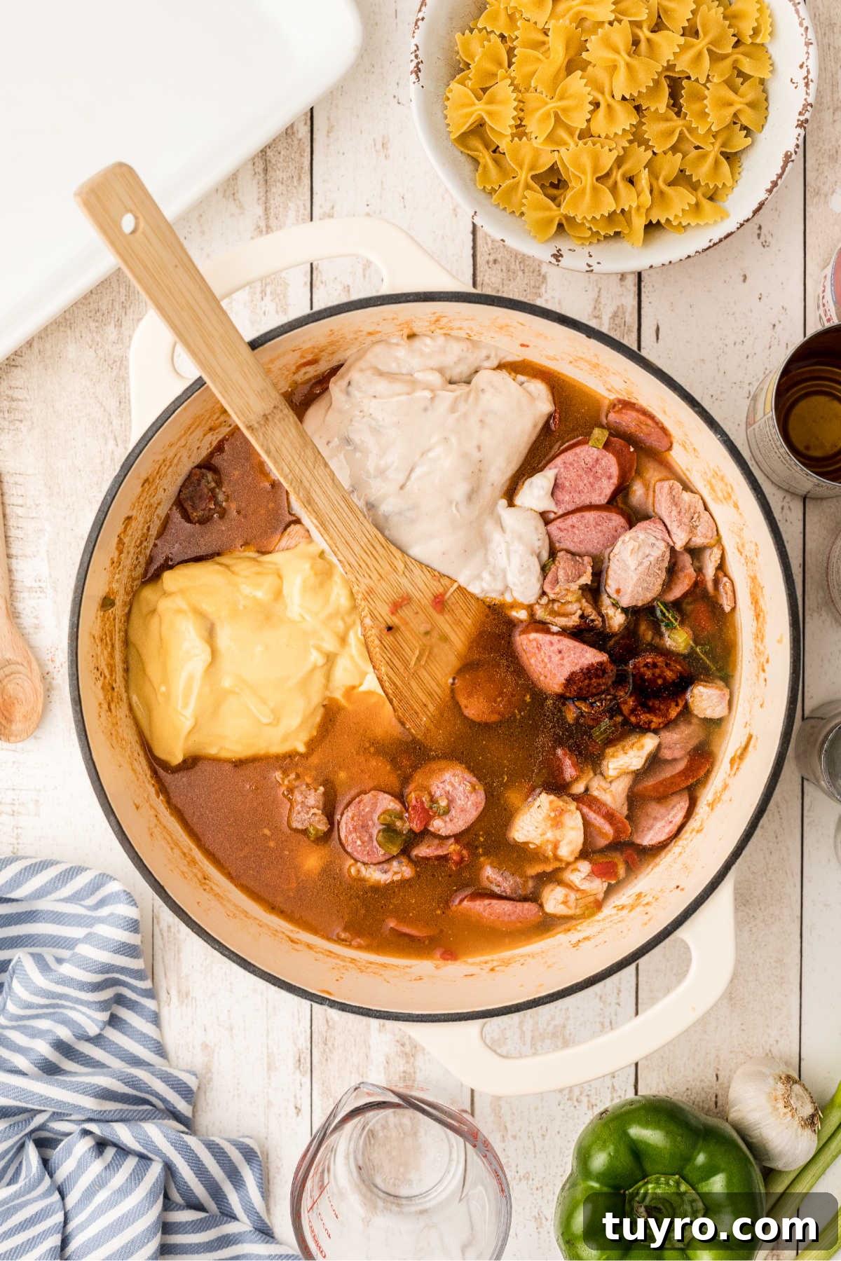 Soups and broths being added to a Dutch oven cooking a pastalaya.