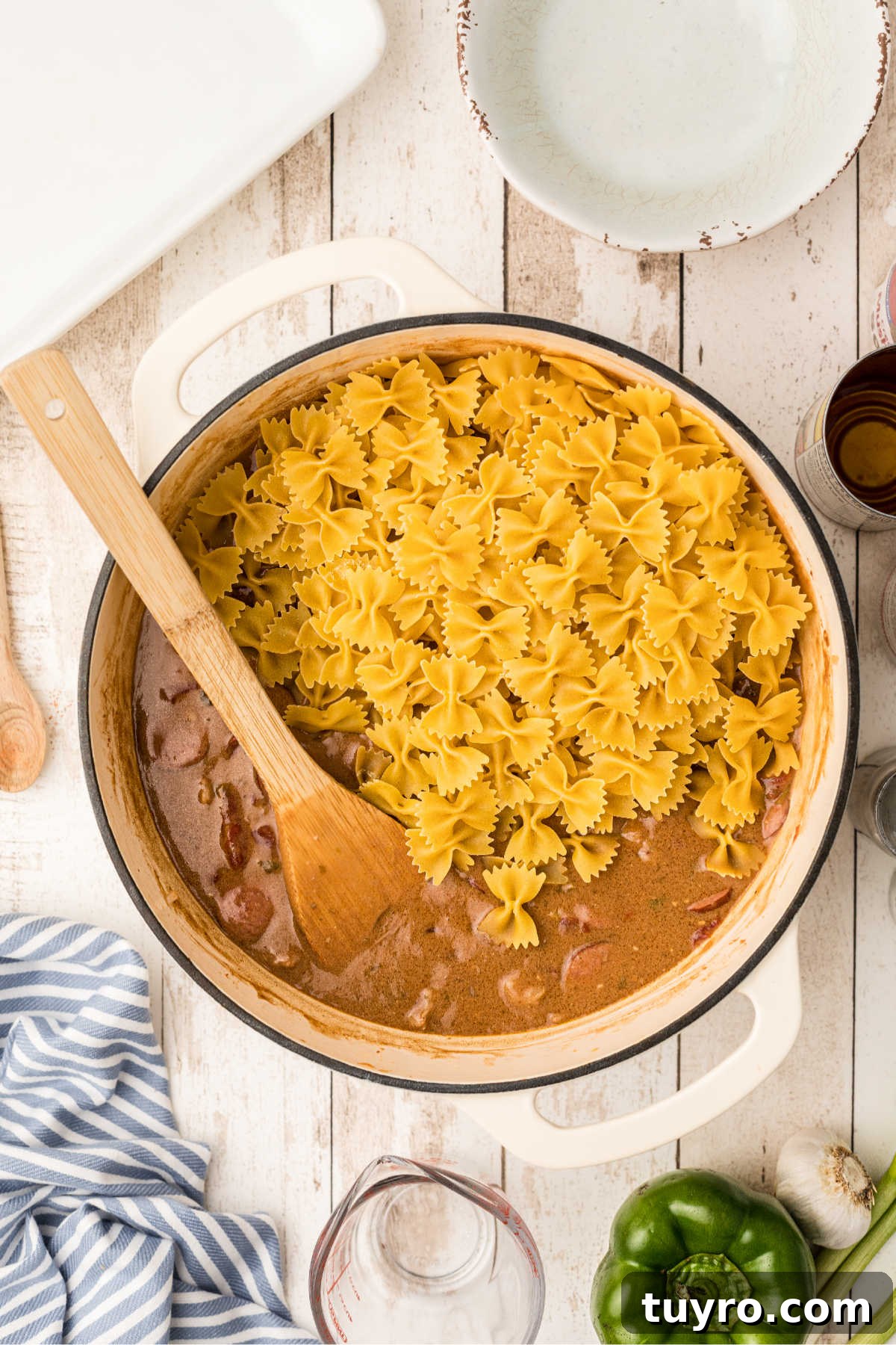 Pasta being added to a Dutch oven with Pastalaya ingredients.