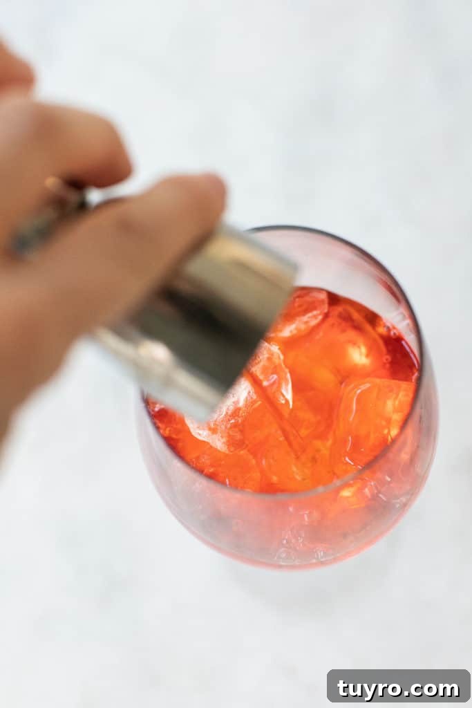 3-Ingredient Aperol Spritz Recipe for Summer Cocktails 4 Pouring Aperol into a glass filled with ice.