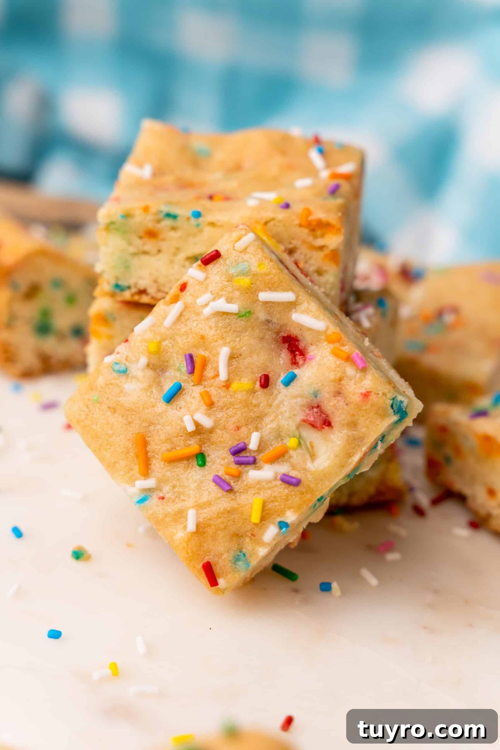 Birthday Cake Blondies Recipe with Sprinkles and Frosting 12 funfetti cake mix cookie bars on a white cutting board