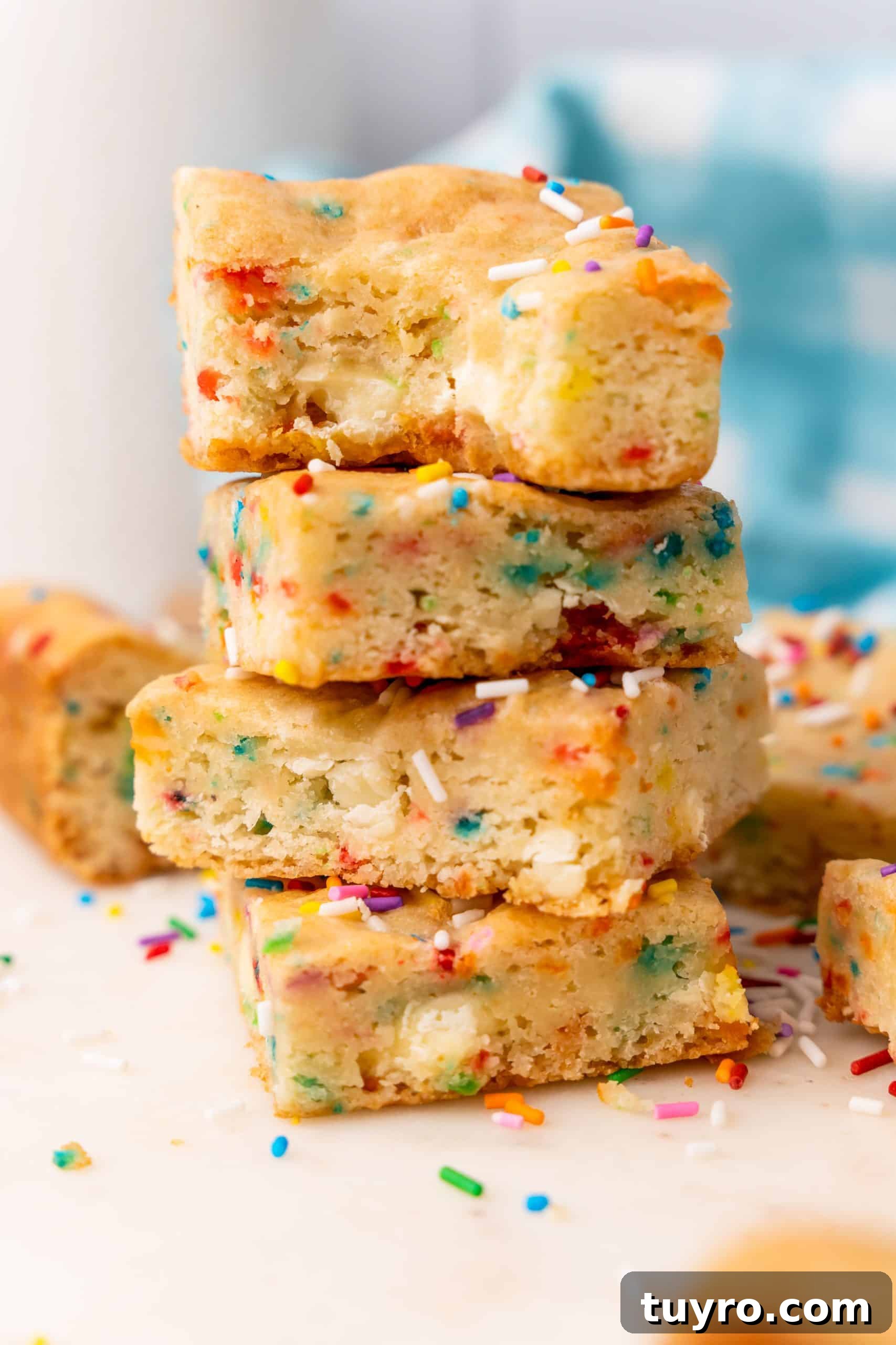 Birthday Cake Blondies Recipe with Sprinkles and Frosting 13 a stack of cake mix cookie bars on a white cutting board