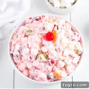 Creamy Fruit Salad with Whipped Topping for Parties 8 A white bowl on the table filled with fruit salad with Cool Whip.
