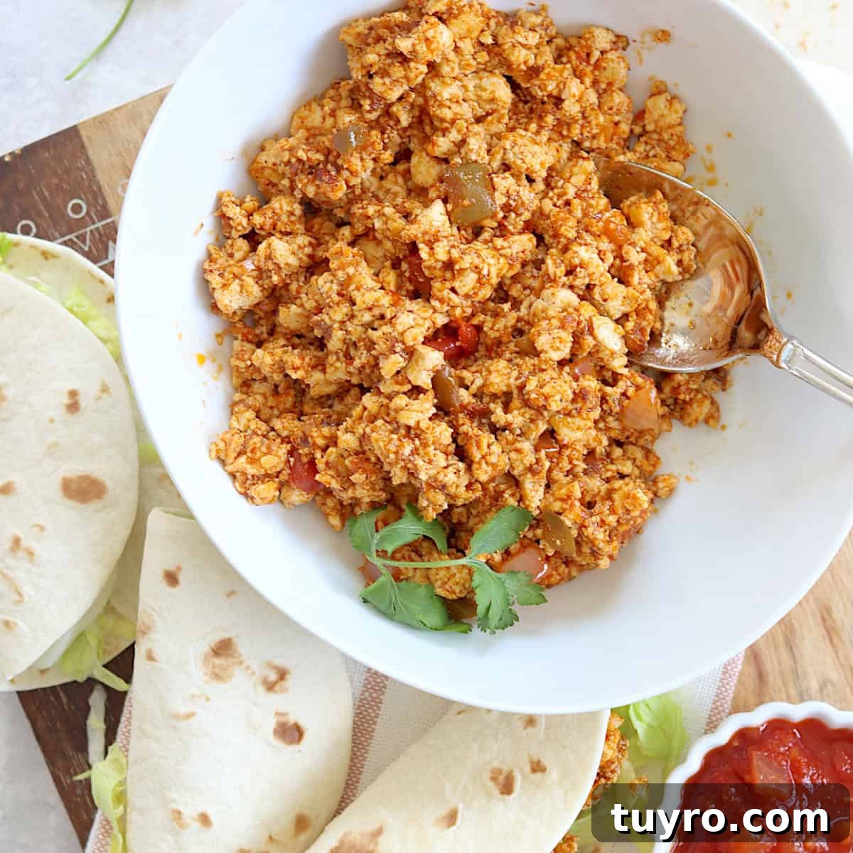 30 Taco Tuesday Ideas for a Craveworthy Dinner 14 Plant based tofu taco meat in a round white bowl and a silver spoon next to two soft shell tacos.