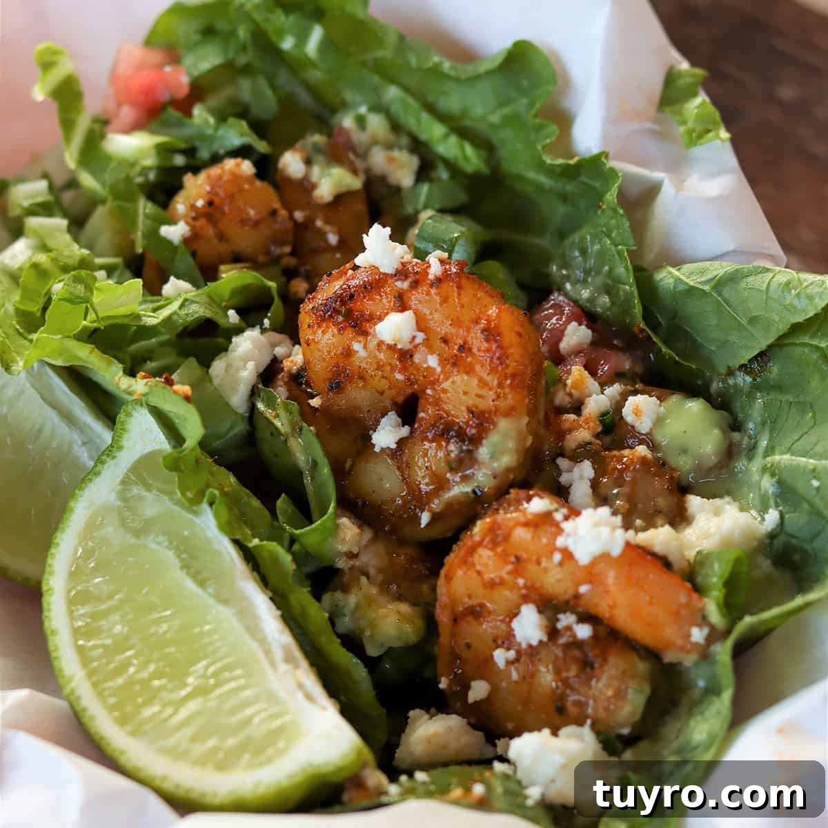 30 Taco Tuesday Ideas for a Craveworthy Dinner 16 Feature image with a closeup of shrimp served in lettuce and garnished with a wedge of lime, cheese, and dressing