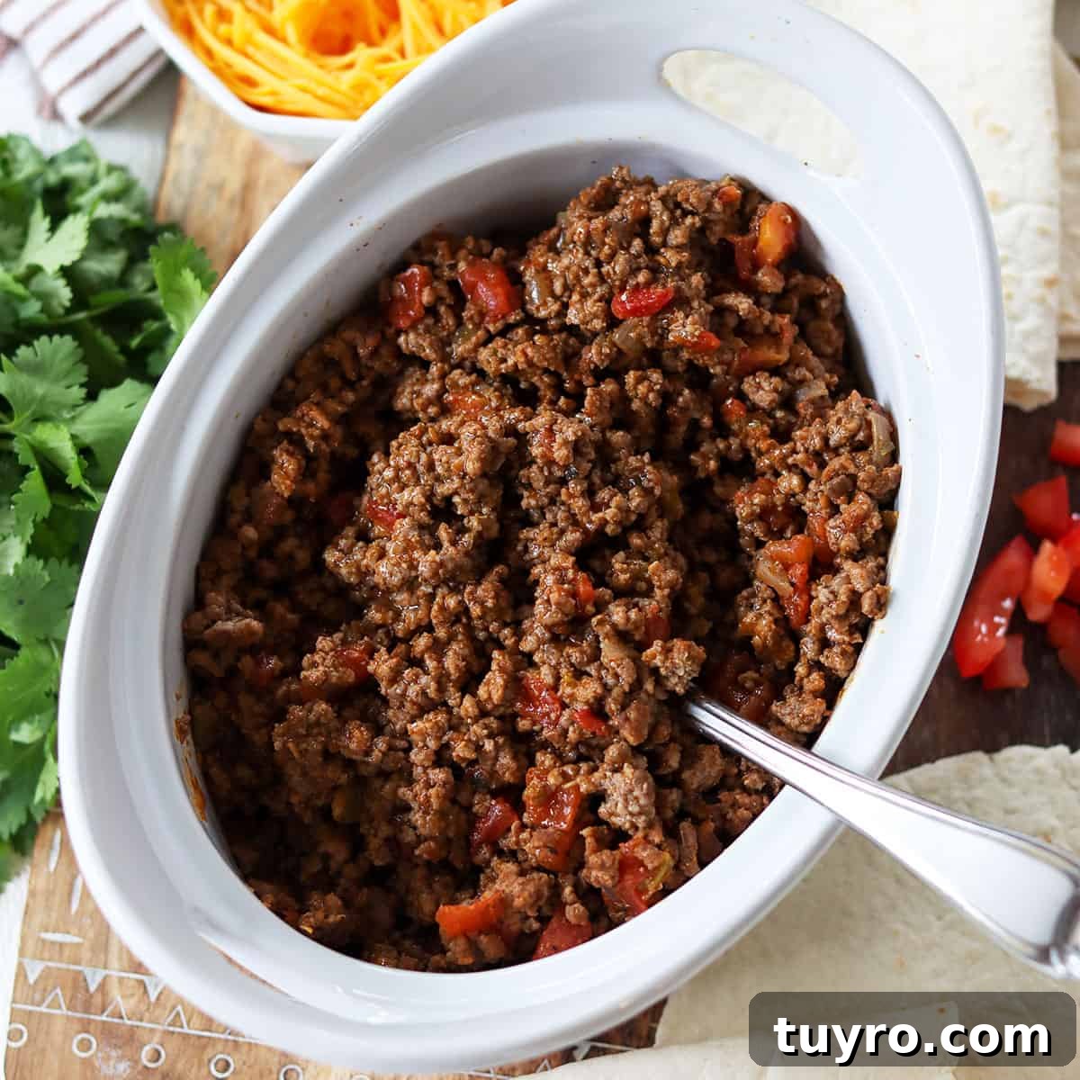 30 Taco Tuesday Ideas for a Craveworthy Dinner 5 Mexican ground beef taco meat ready to be served in a white bowl surrounded by taco shells, cheese, and tomatoes