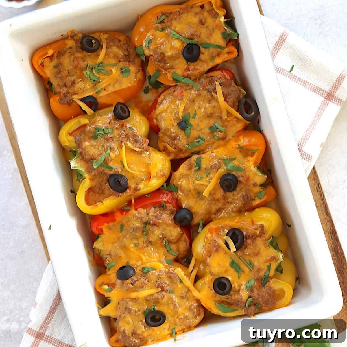 30 Taco Tuesday Ideas for a Craveworthy Dinner 7 A white baking dish of stuffed taco peppers with melted cheese and olives on top.