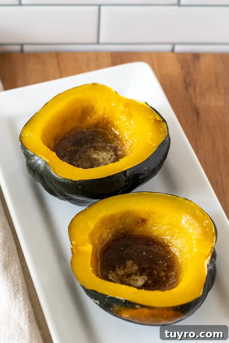 Baked acorn squash with butter and brown sugar on white platter.