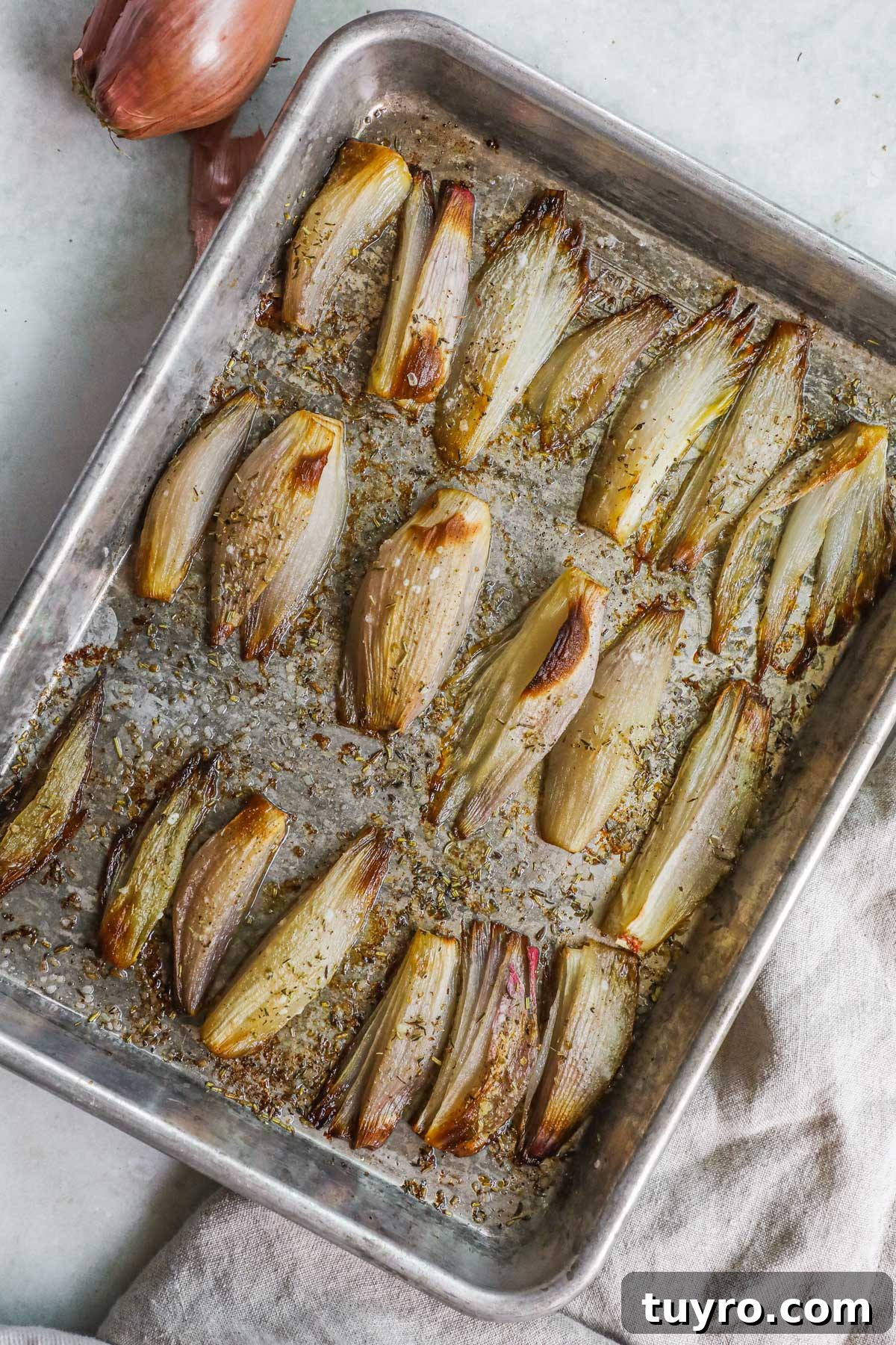 Crispy Roasted Shallots with Balsamic Glaze 2 Roasted caramelized shallots on a baking sheet with dried herbs.