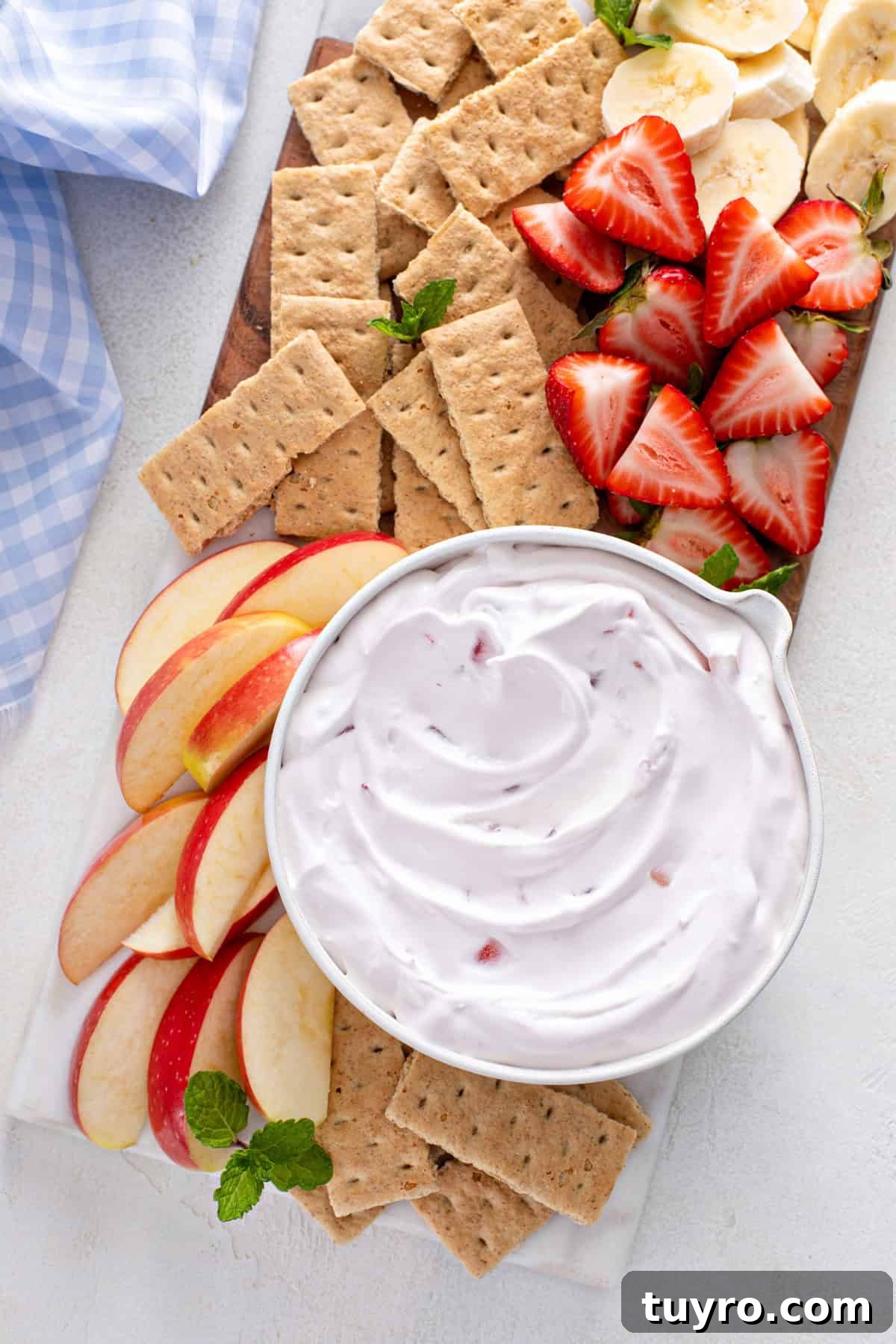 Overhead view of a bowl of yogurt fruit dip on a platter surrounded by graham crackers and fresh fruit.