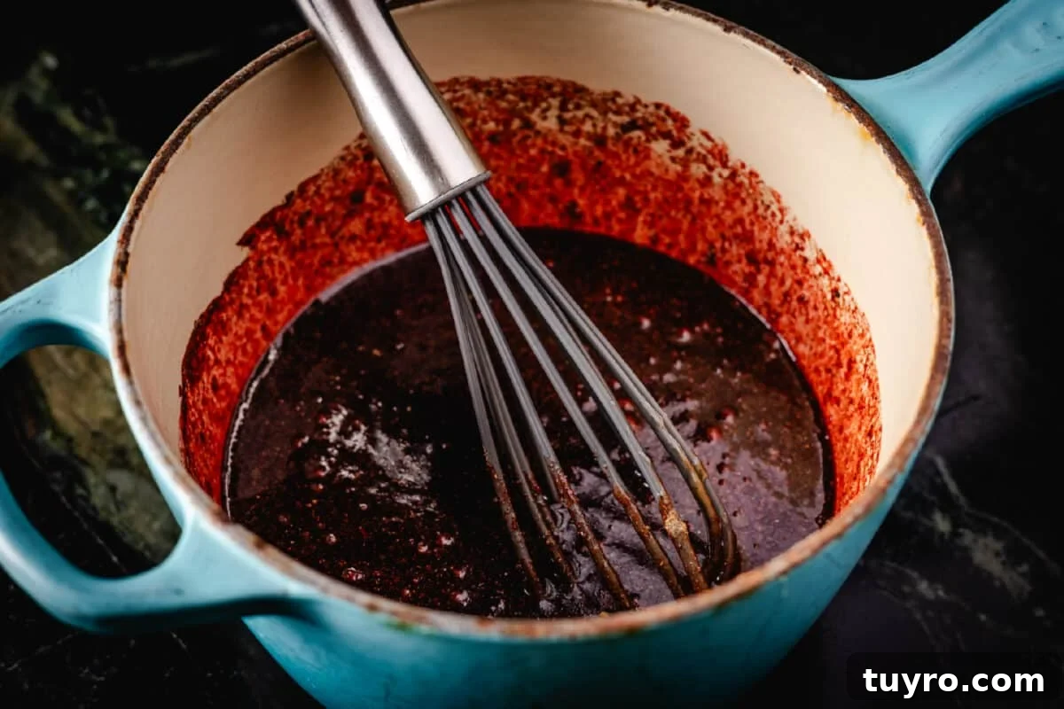 Authentic Cantonese Char Siu Pork Recipe: Smoky Oven-Roasted BBQ 4 A whisk resting in a blue pot of sauce.