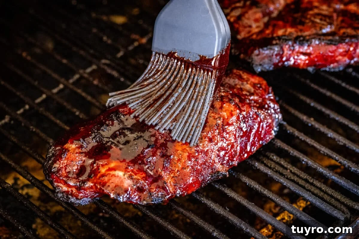 Authentic Cantonese Char Siu Pork Recipe: Smoky Oven-Roasted BBQ 6 A basting brush applying char siu sauce to pork sitting on the grates of a smoker.