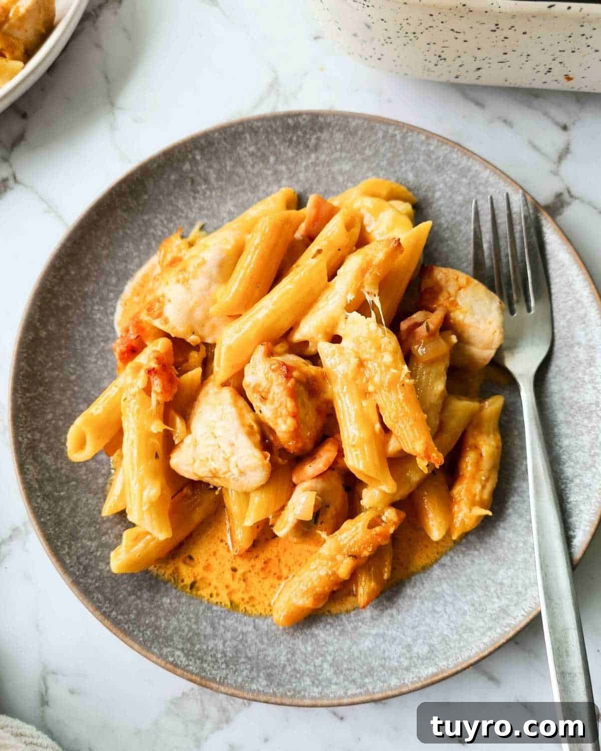 Creamy Chicken & Bacon Pasta Bake Recipe for Weeknight Dinners 9 Close up of a creamy pasta on a grey plate with a fork