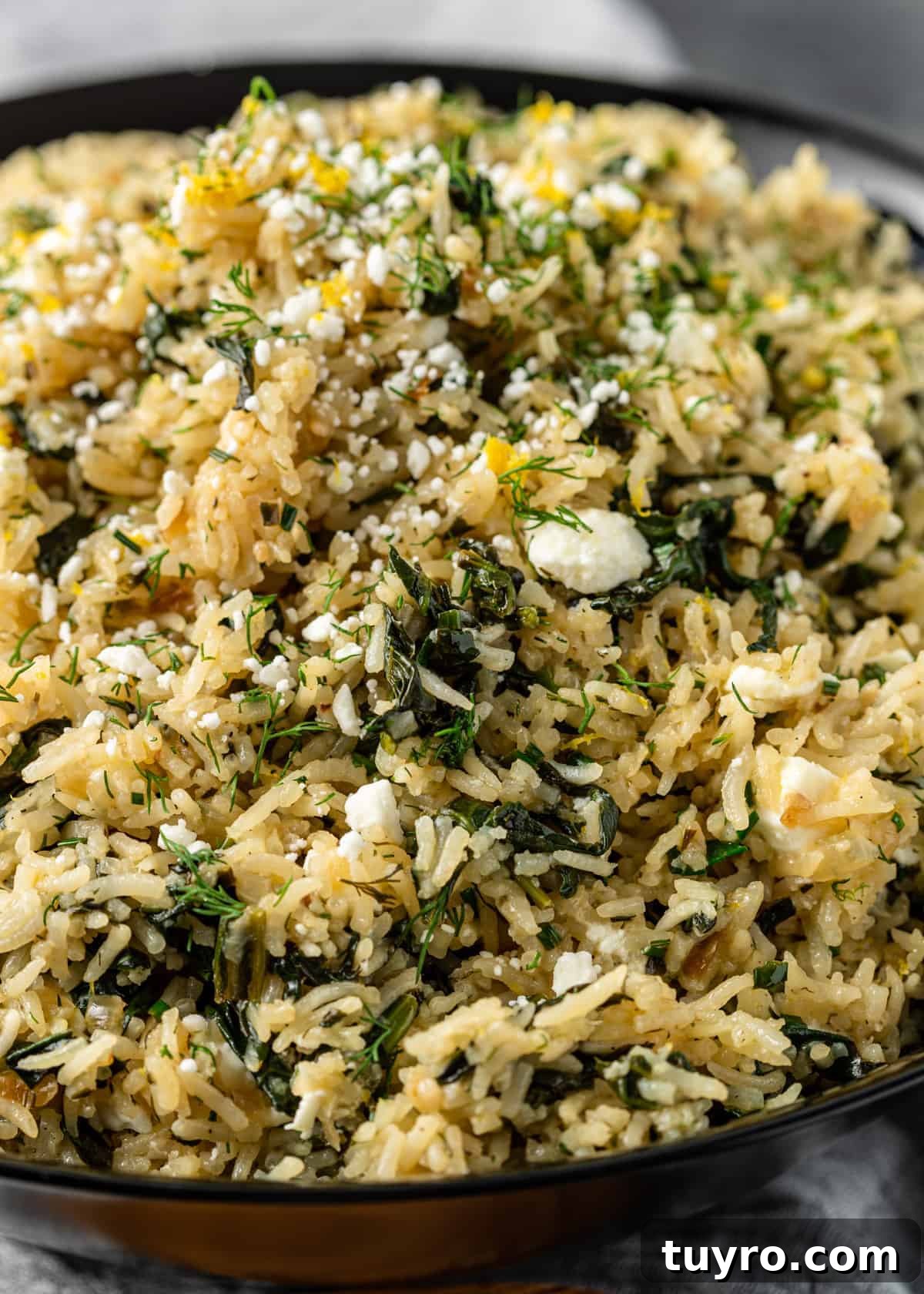close up: bowl of long grain rice with spinach, lemon, feta cheese and Greek seasoning