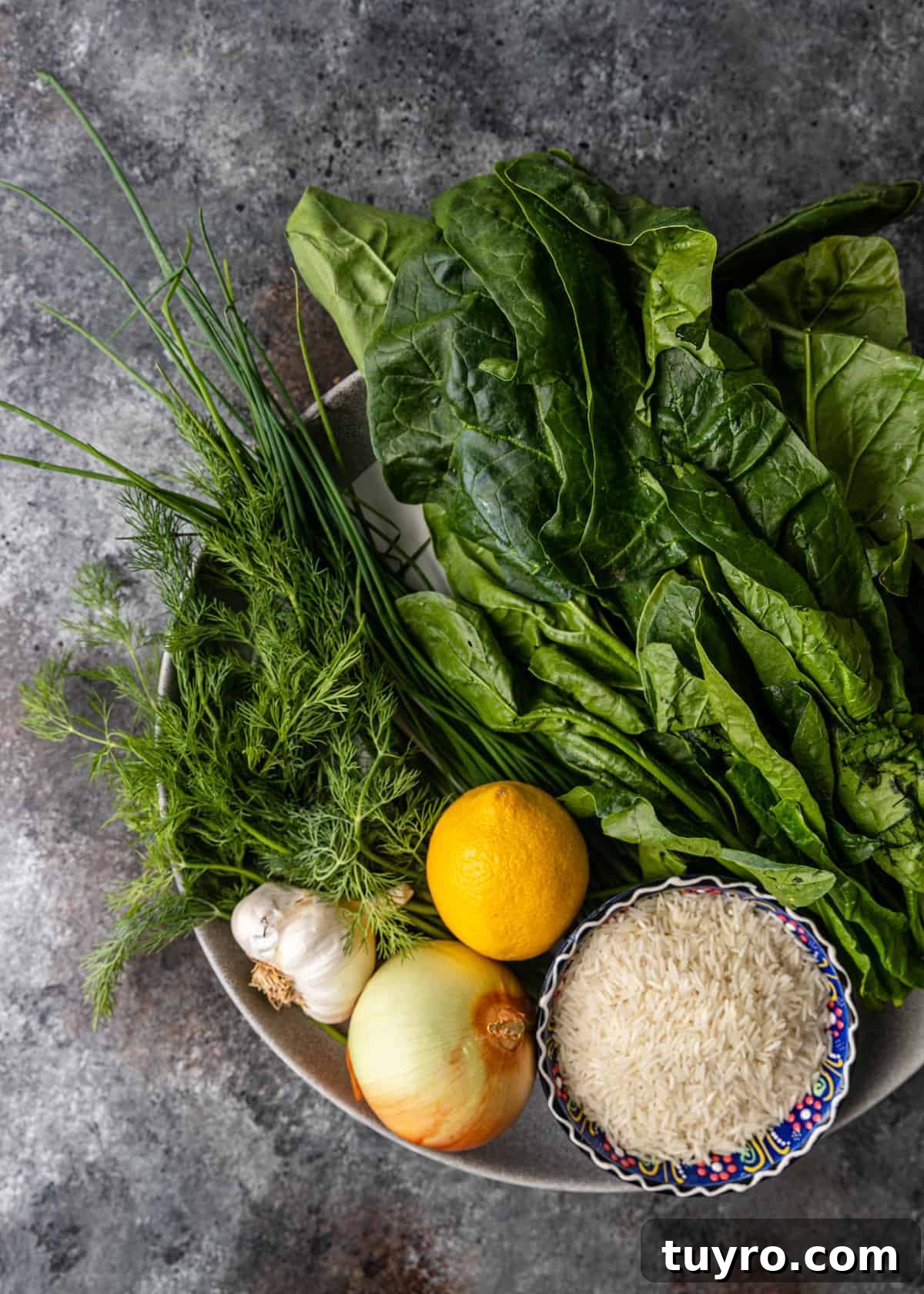 bowl full of fresh spinach, garlic, lemon, rice, and other ingredients to make spanakorizo