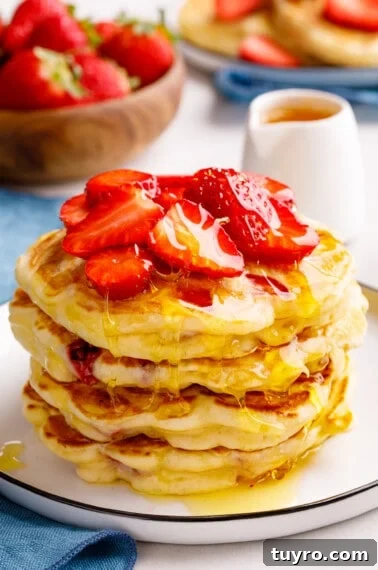 Fluffy Homemade Strawberry Waffles Recipe 9 A stack of strawberry pancakes topped with chopped strawberries.