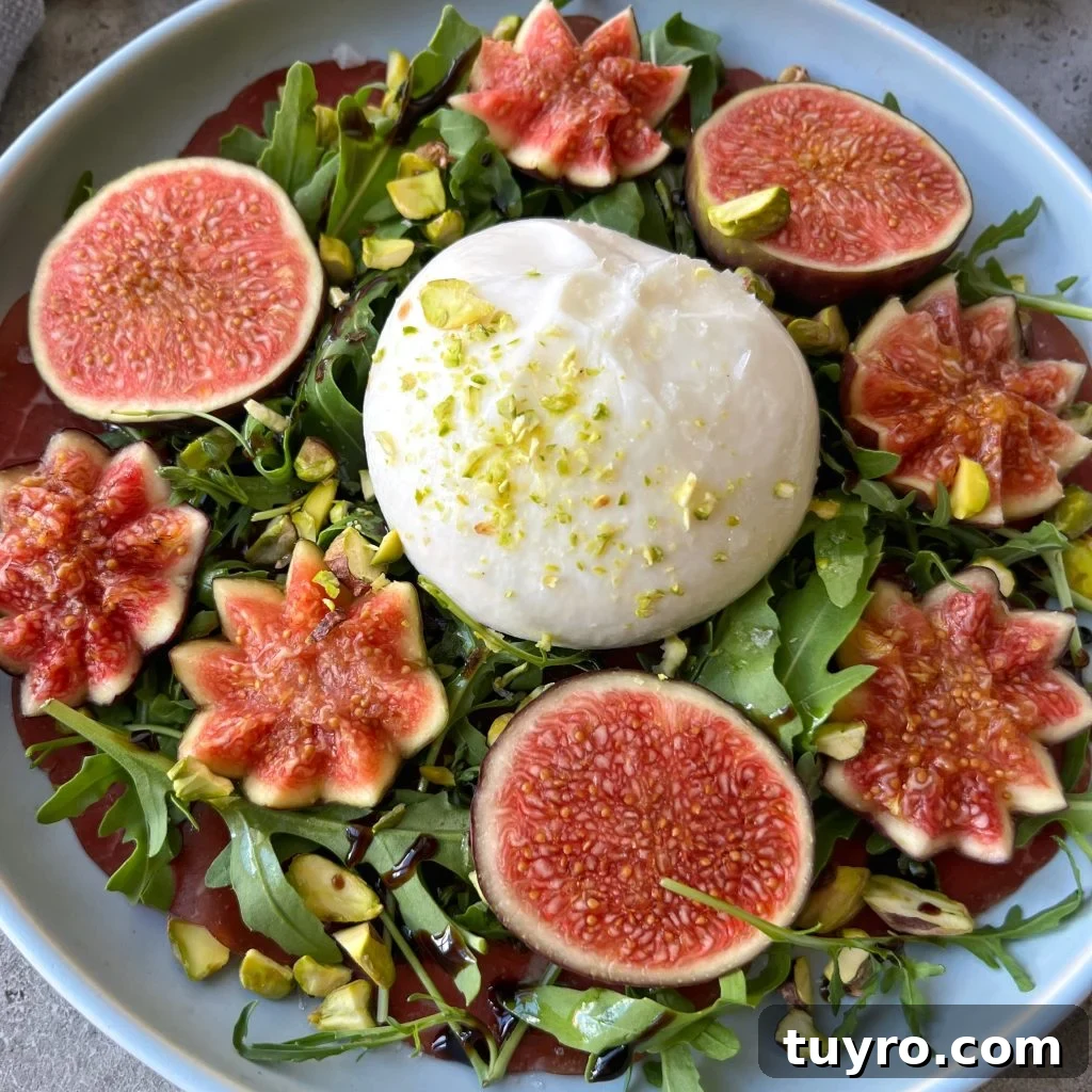 Fig and Bresaola Salad with Arugula, Burrata & Balsamic 2 A plate of bresaola, fresh arugula topped with whole burrata cheese, surrounded by decorative fig slices, sprinkled with pistachios, and drizzled with balsamic glaze.