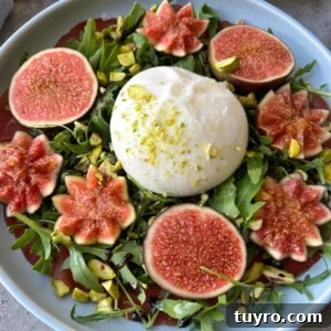 Fig and Bresaola Salad with Arugula, Burrata & Balsamic 4 A plate of fresh arugula topped with whole burrata cheese, surrounded by decorative fig slices, sprinkled with pistachios, and drizzled with balsamic glaze—one of those irresistible bites perfect for health-minded food recipes.