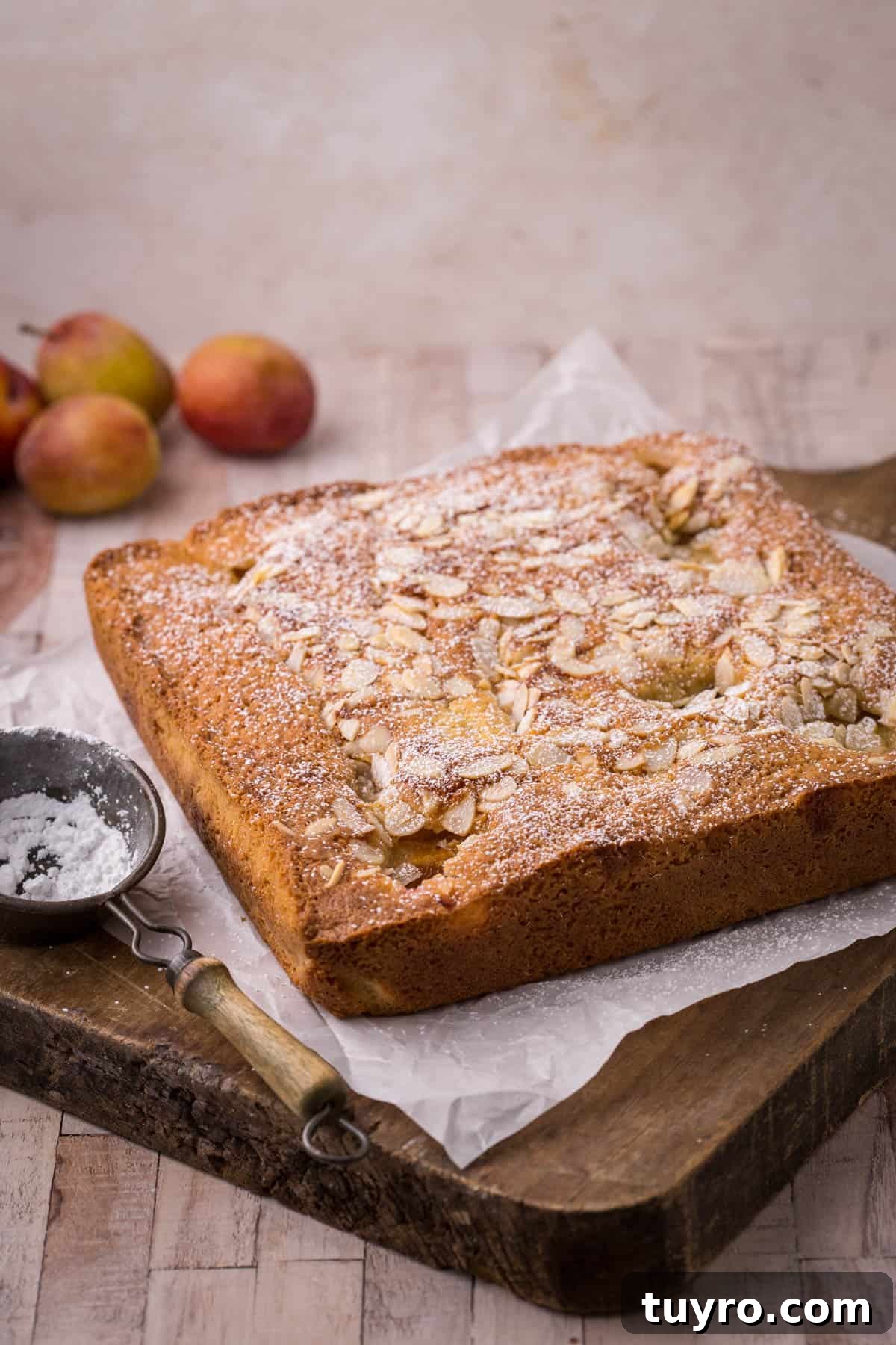 Whole gluten-free plum cake with icing sugar dusted over.