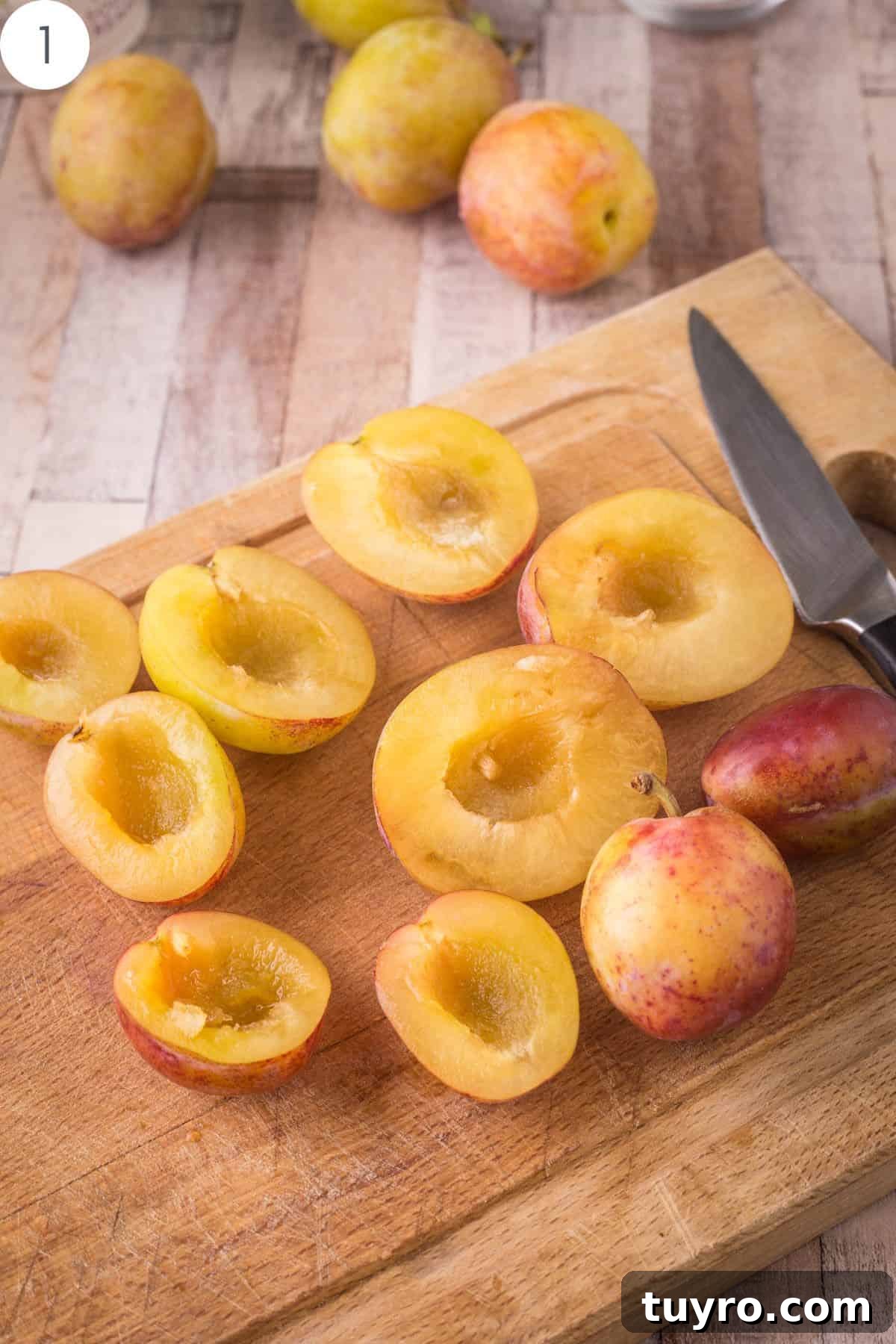 Halved plums with stones removed on a wooden board.