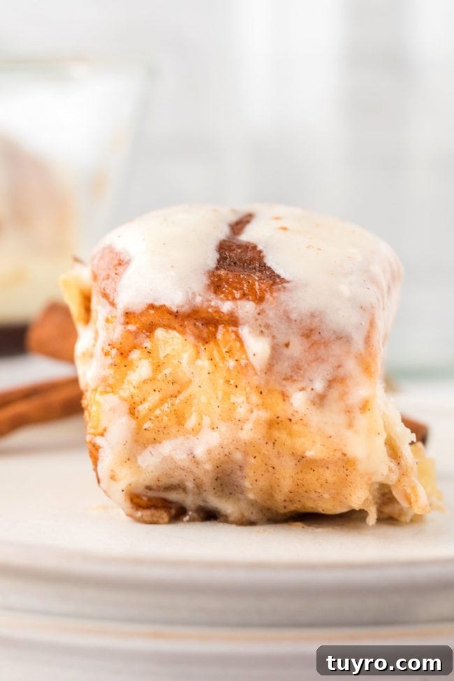 30-Minute Homemade Cinnamon Rolls 7 close up of a homemade cinnamon bun on a stack of white plates with a cinnamon stick