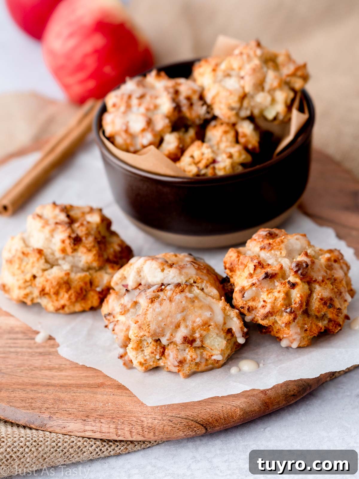 Crispy Air Fryer Apple Fritters Recipe 2 Glazed apple fritters in a bowl and on parchment paper.