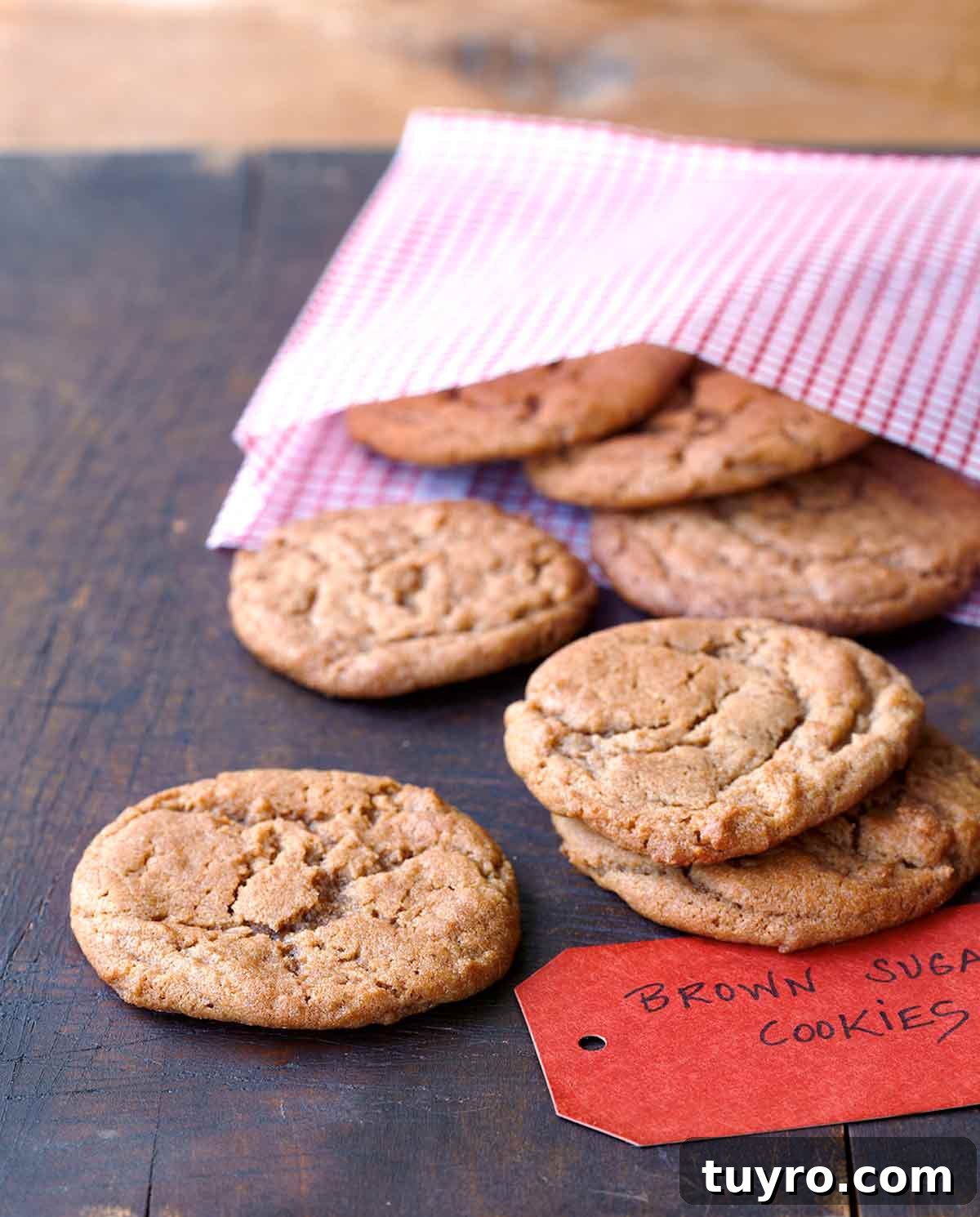 Brown Sugar Cookies: Chewy, Buttery Caramel Flavor 2 A wooden table with a pink gingham bag with 7 brown sugar cookies in it and a label.