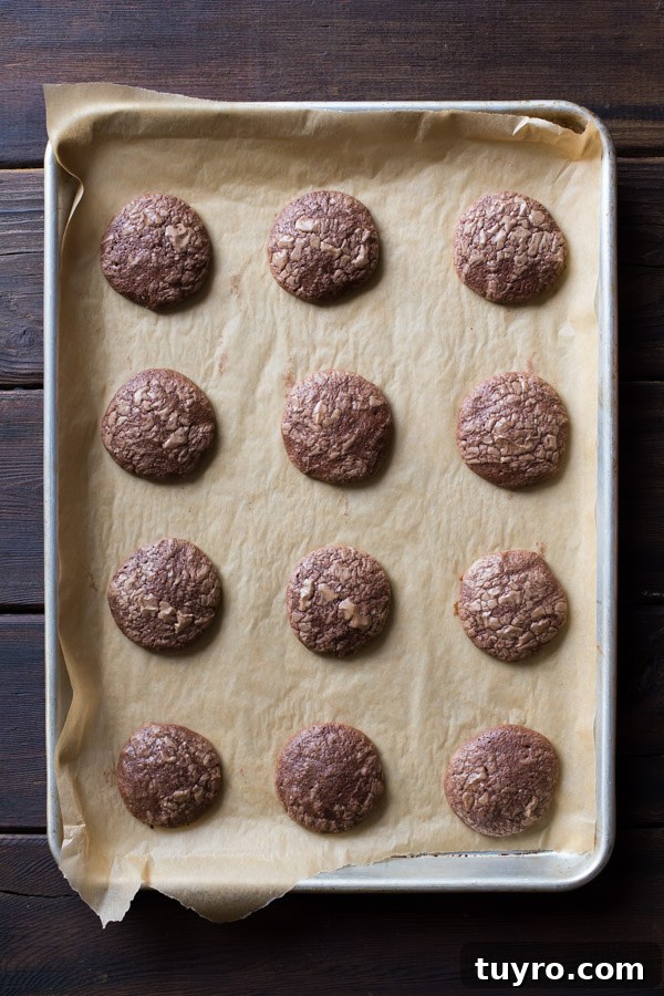 How to Make Soft, Chewy Brownie Cookies 3 Soft and Chewy Brownie Cookies on a parchment paper lined baking sheet.