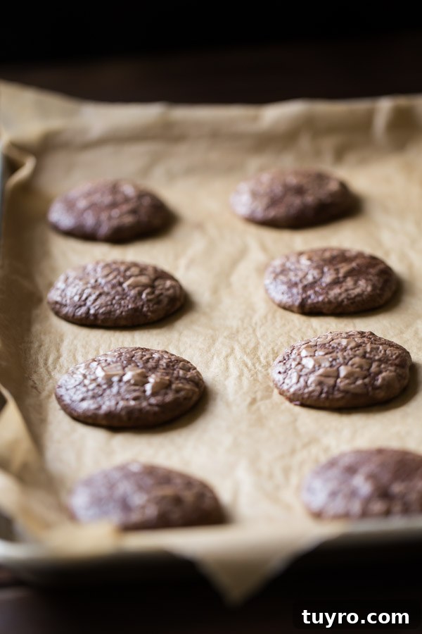 How to Make Soft, Chewy Brownie Cookies 4 Soft and Chewy Brownie Cookies on a parchment paper lined baking sheet.