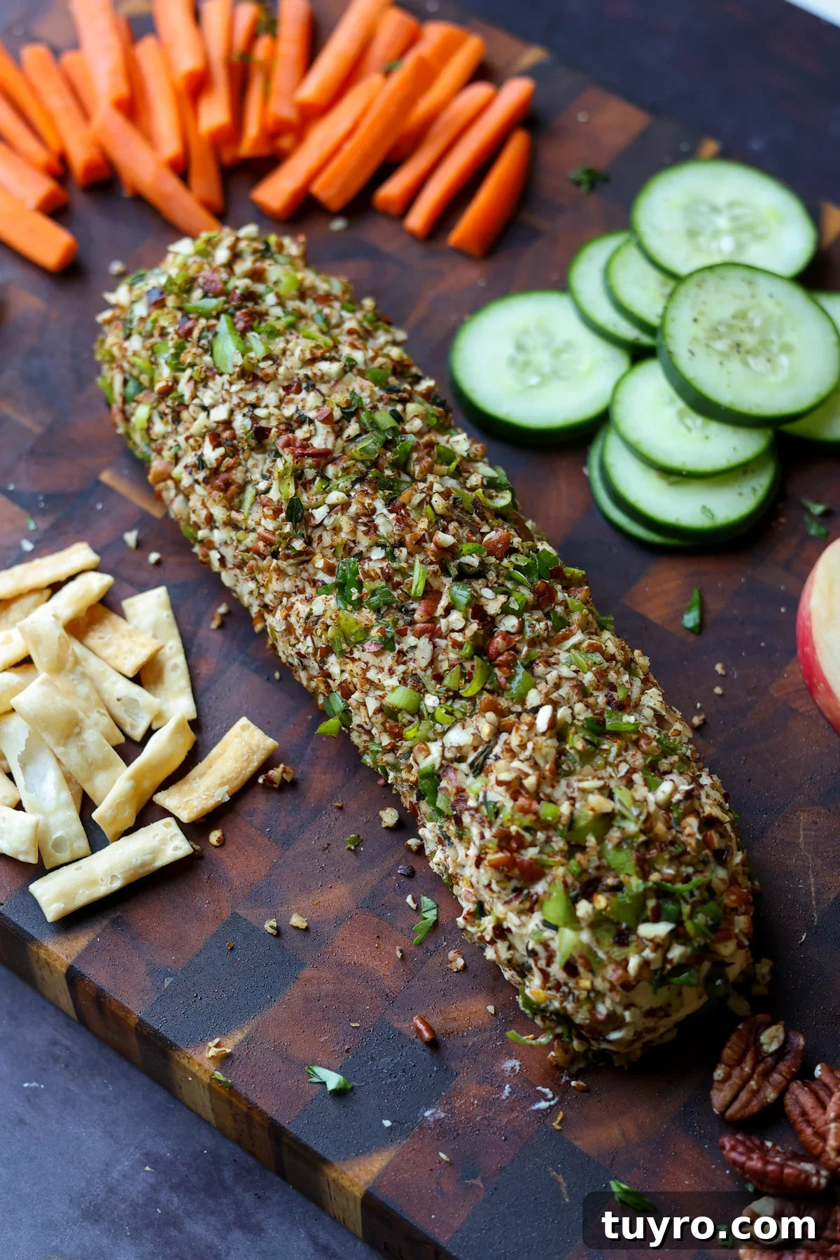 Festive Vegan Cheese Log Recipe for Holiday Parties 2 holiday cheese log on a party platter with veggies, chips, pita, and apple slices