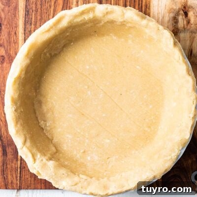 Flaky Almond Flour Pie Crust Recipe for Perfect Pastries 11 An almond flour pie crust in a white pie plate, shown sitting on a cutting board.