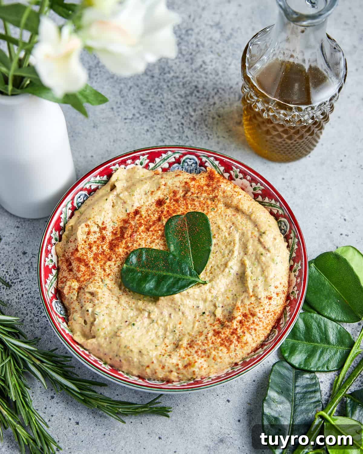 Vegan Whipped Feta Dip with Pistachios Lime Leaves and Rosemary 8 Photo of vegan whipped feta dip on a grey background with ingredients around the outside.