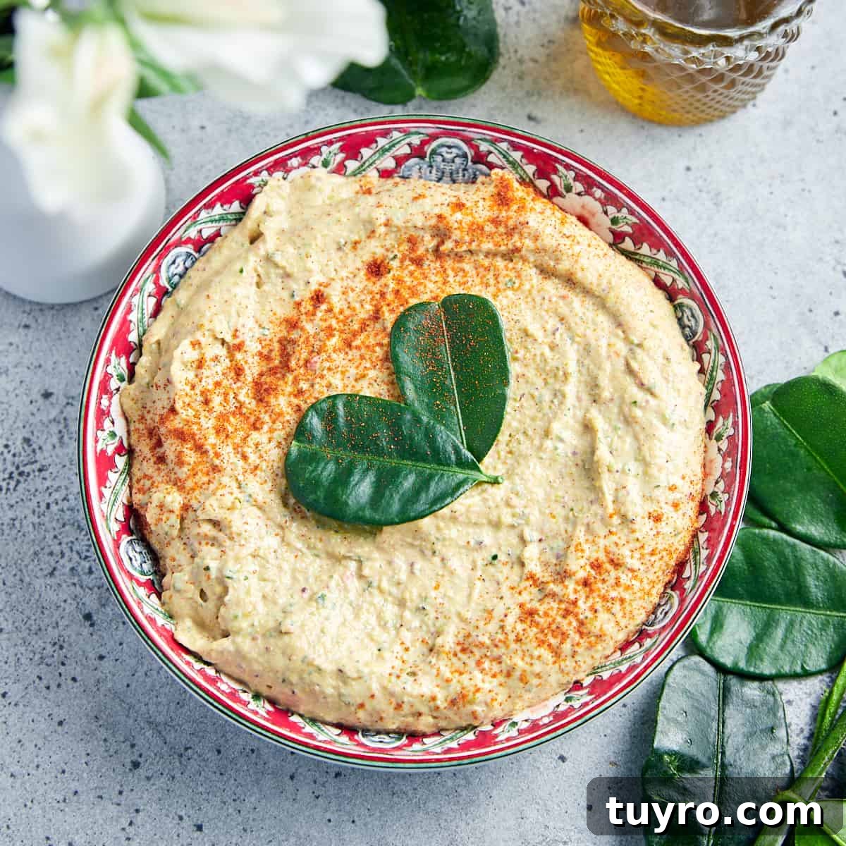Vegan Whipped Feta Dip with Pistachios Lime Leaves and Rosemary 9 Square overhead photo of vegan whipped feta and pistachio dip on a grey background with lime leaves and olive oil and white flowers around.