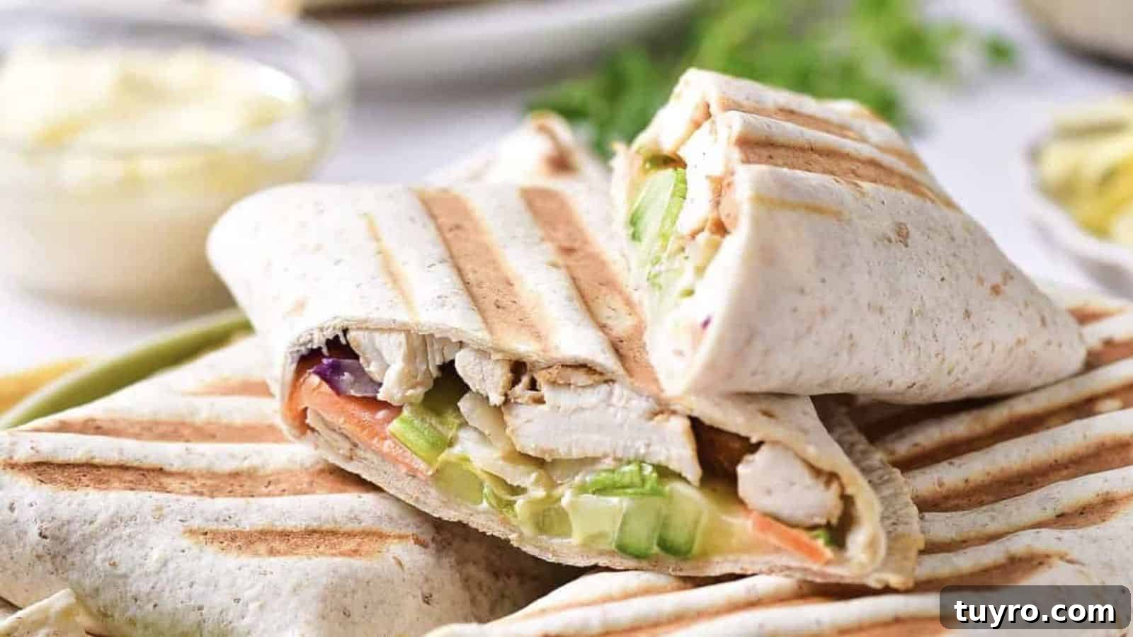 Grilled wraps filled with sliced chicken, lettuce, cucumber, and carrots, stacked on a plate with grill marks visible on the tortillas.