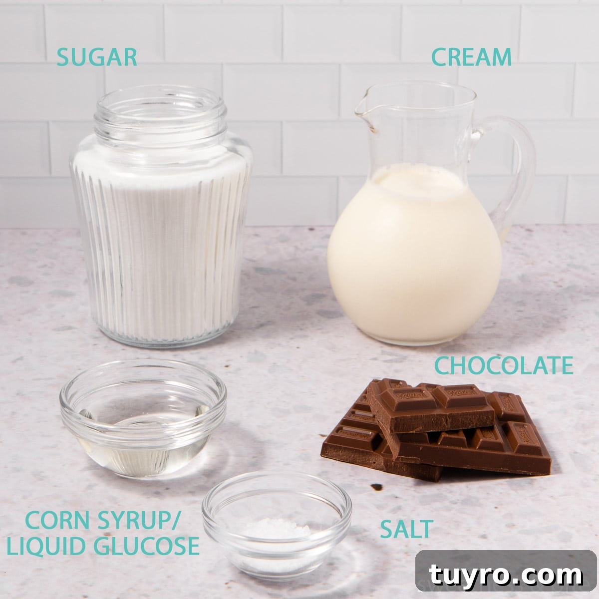 Decadent Chocolate Caramel Sauce Recipe for Desserts 3 The ingredients for chocolate caramel sauce in glass containers on a grey background - sugar, cream, corn syrup, salt and chocolate.