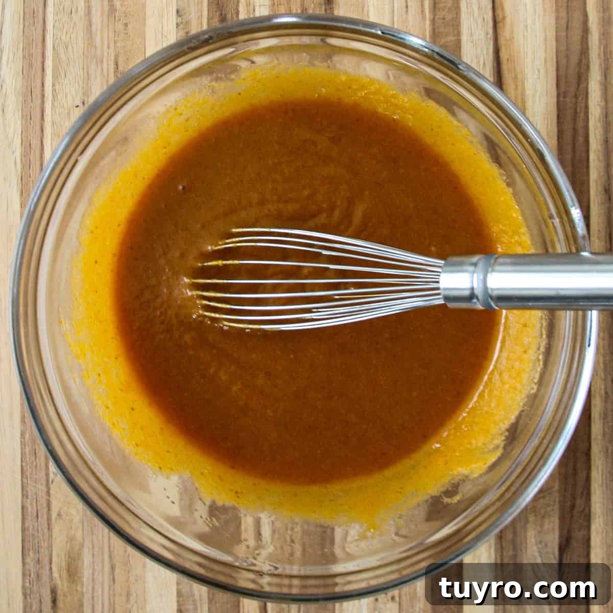 Gluten Free Pumpkin Bread Recipe 6 A mixture of oil, pumpkin puree, egg, sugar, and vanilla in a glass bowl with a whisk.