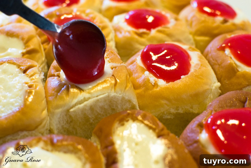 Spooning guava glaze on top of cream cheese custard filled rolls