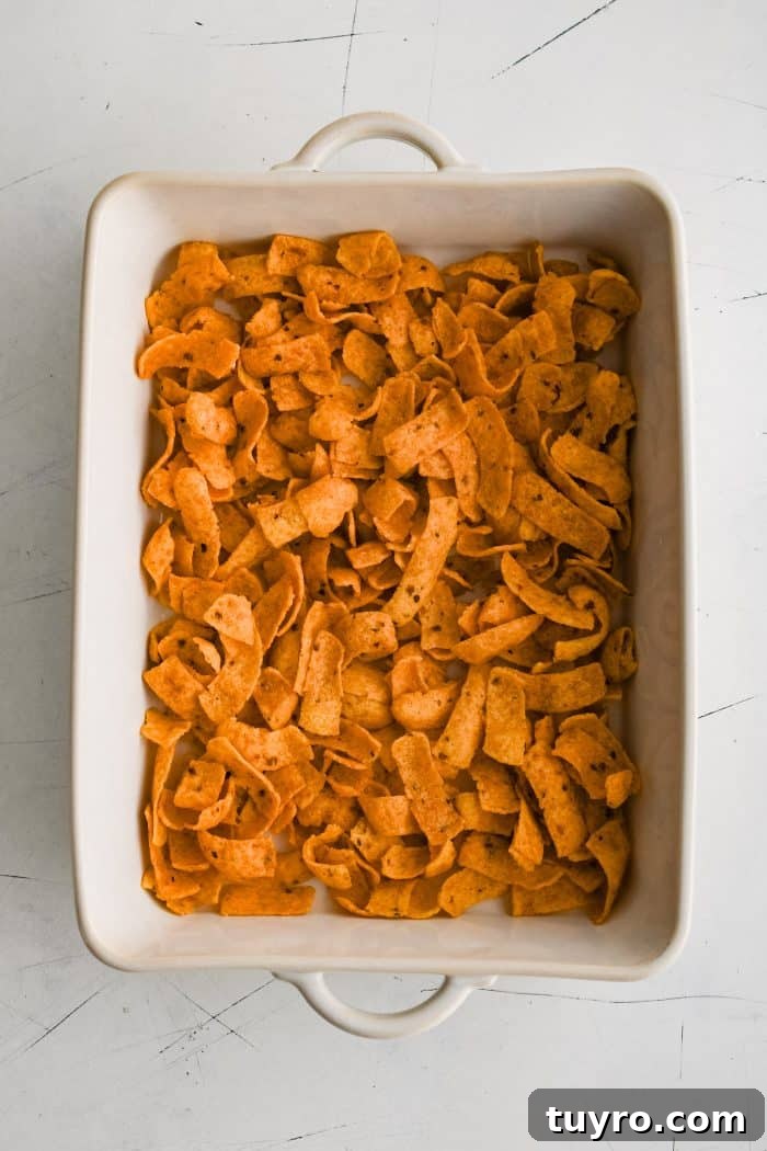 Large white ceramic casserole dish filled with a layer of Fritos.