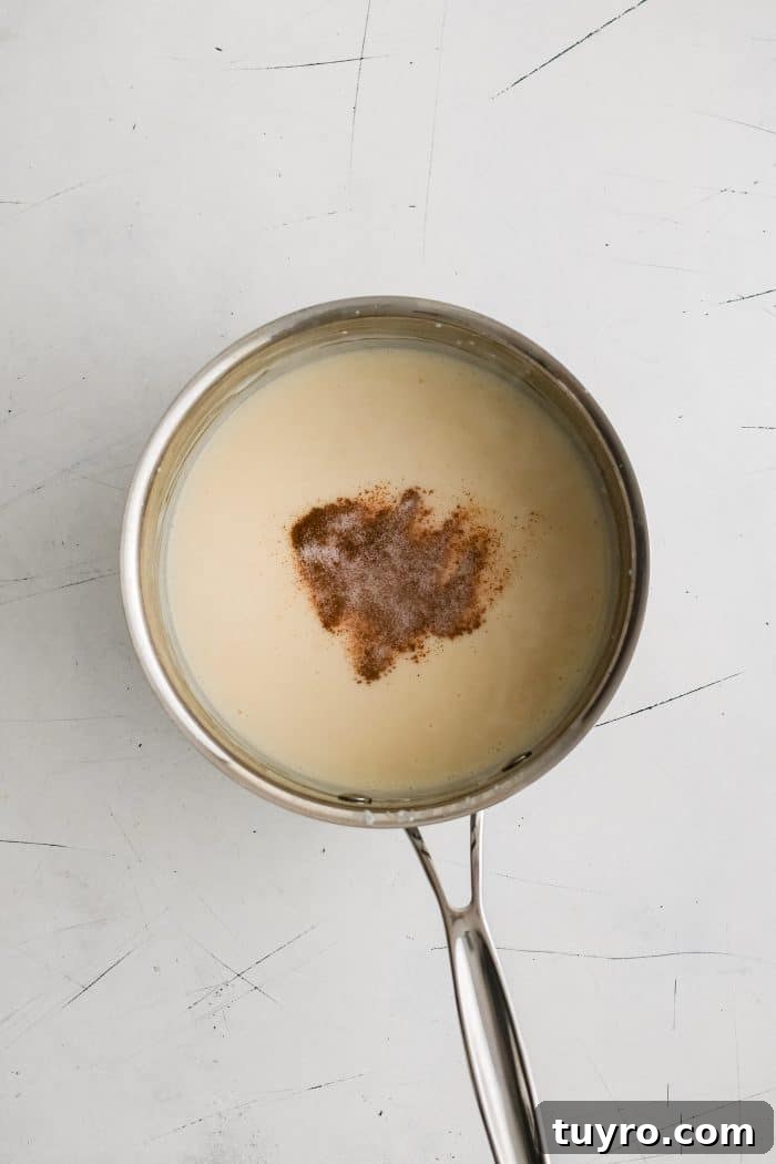 Chili powder added to a saucepan filled with homemade béchamel sauce.