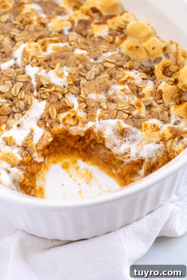 Close up of a scoop missing from Sweet Potato Casserole with Marshmallows and Oat Streusel showing the inside of the casserole.
