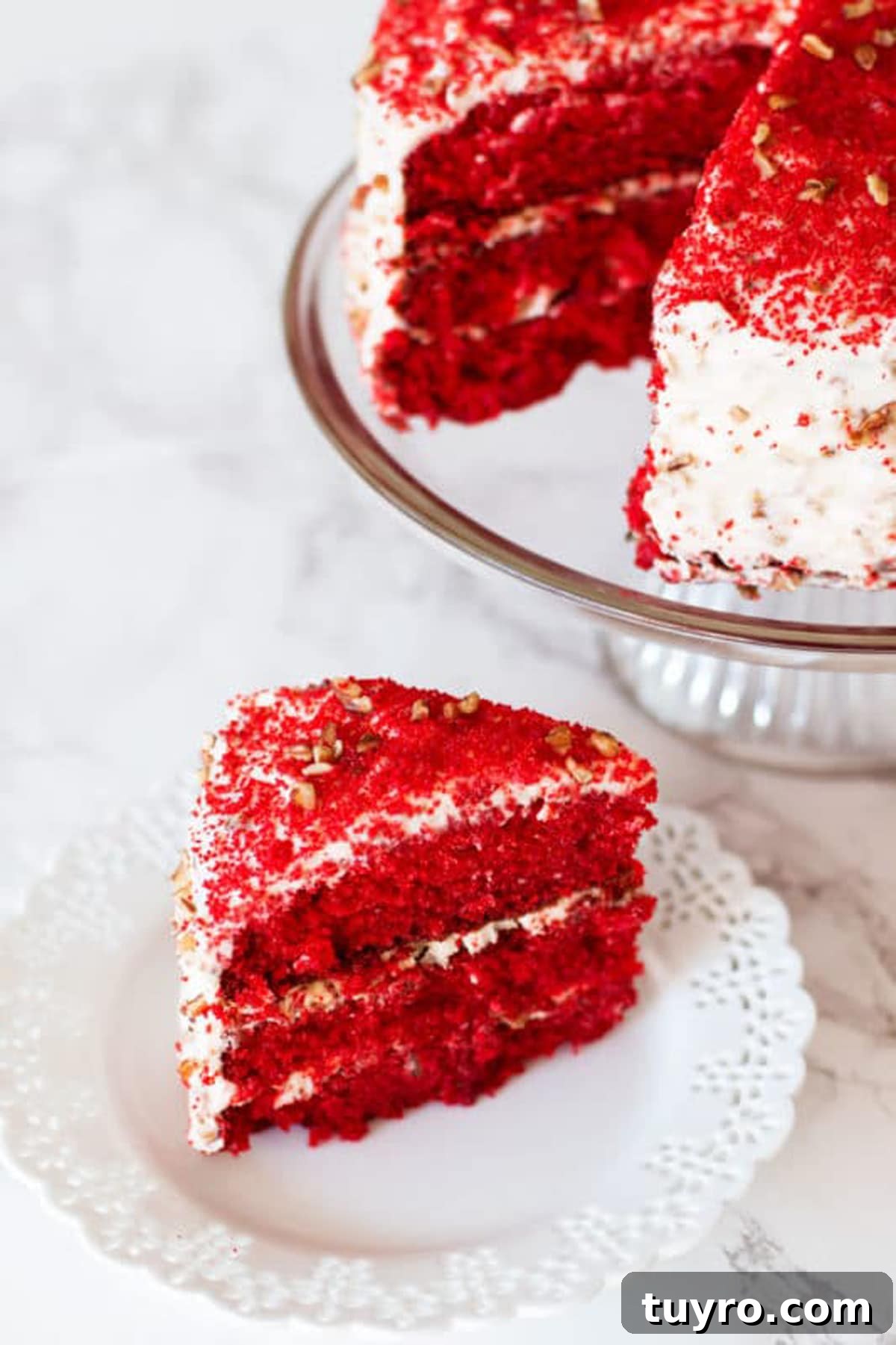 Classic Red Velvet Cake with Cream Cheese Frosting 18 Sliced Red Velvet Cake sitting on a glass cake dish, slice of cake on a white lace plate.