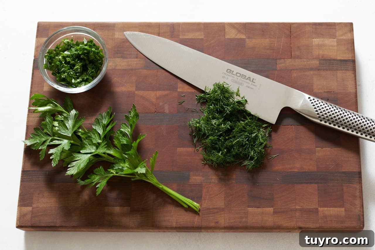 Chilled Beet Borscht: Classic Cold Soup Recipe 5 Chopped dill and fresh parsley on a cutting board with a knife.
