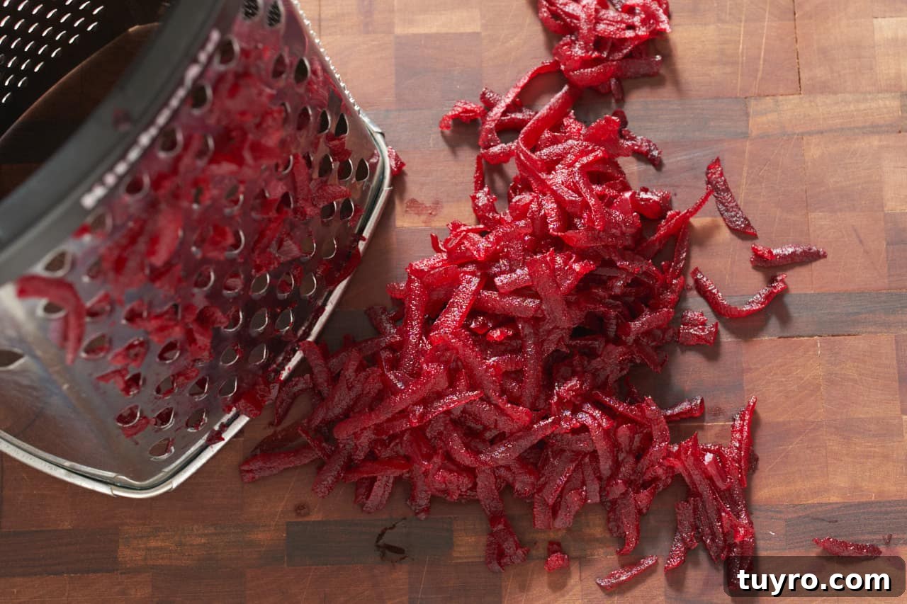 Chilled Beet Borscht: Classic Cold Soup Recipe 6 Grated beets next to a box grater on a cutting board.