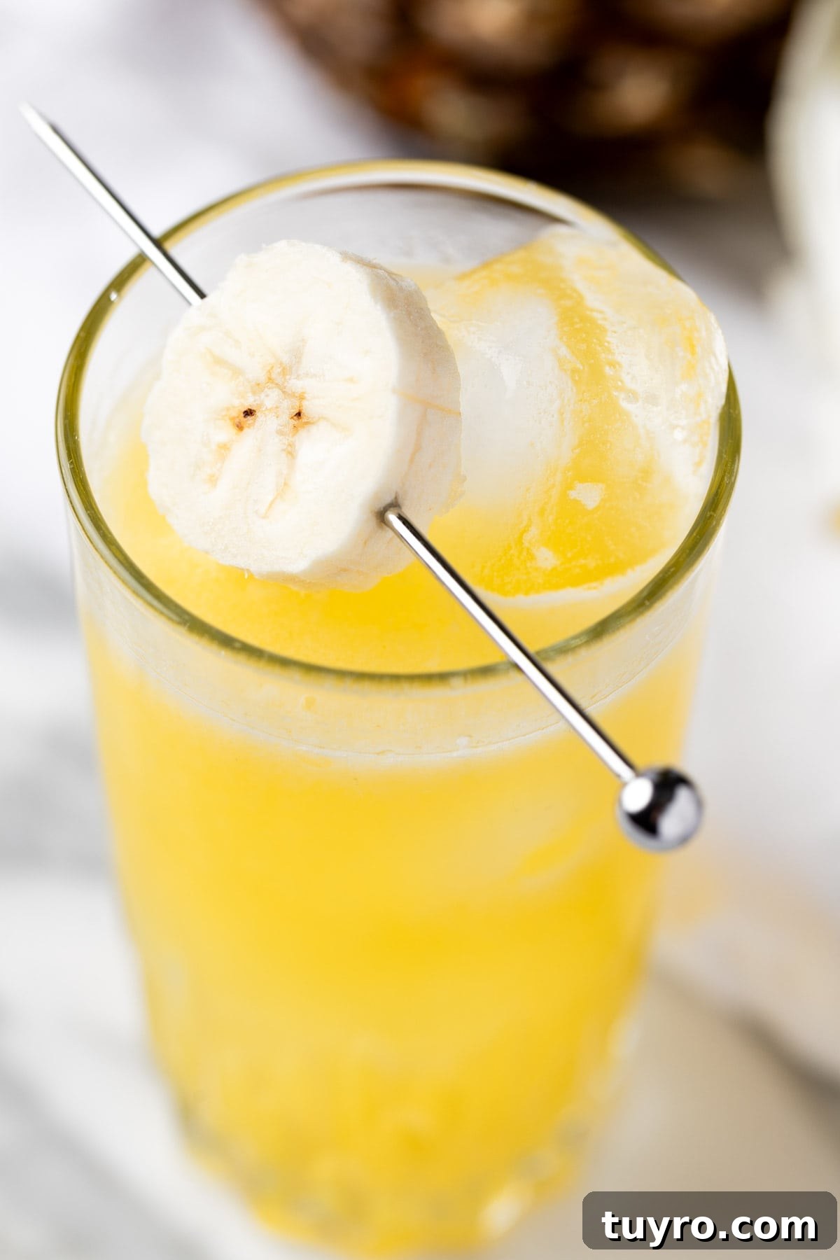 Creamy Banana Rum Cocktail Recipe 2 A banana rum cocktail garnished with banana slices.